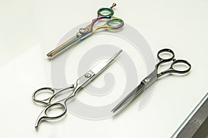 Various types of barber scissors on a white wooden surface