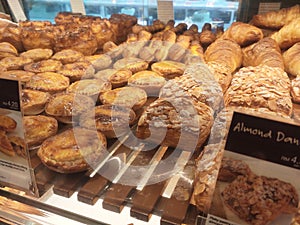 Various types of breads are displayed for sale inside the bakery display rack.