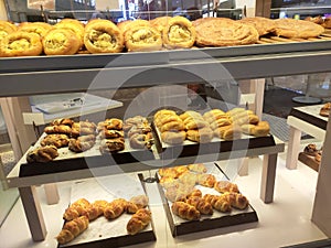 Various types of breads are displayed for sale inside the bakery display rack.