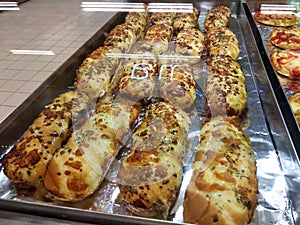 Various types of breads are displayed for sale inside the bakery display rack.