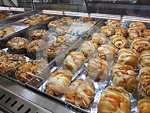 Various types of breads are displayed for sale inside the bakery display rack.