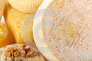Various types of cheese displayed with honey and nuts on a wooden surface