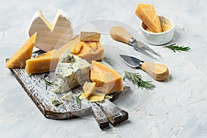 Various types of cheese Piece of Parmesan cheese, dor blu, camamber brie with knife on a light background. top view