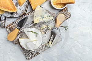 Various types of cheese Piece of Parmesan cheese, dor blu, camamber brie with knife on a light background. top view