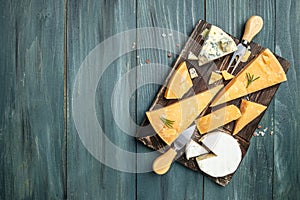 Various types of cheese Piece of Parmesan cheese, dor blu, camamber brie with knife on a wooden board. top view