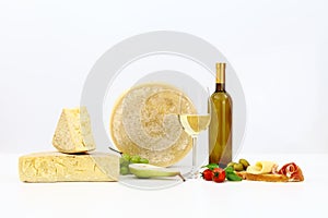 various types of cheese with wine, tomatoes, basil, olives, ham, grapes, pears and bread