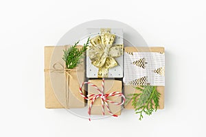 Various types of Christmas New Year gift boxes in craft and silver paper tied with twine golden ribbon on white background