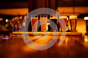 Various types of craft beer in small glasses on a wooden table in a pub. photo