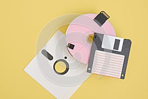 various types of disks for storing information on a yellow background, modern and retro disks and floppy disks
