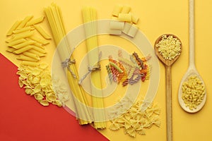 Various types of dry pasta : spaghetti, penne, farfalle, tagliatelle, fettuccine on a bright yellow background.Top view.