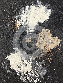 Various types of flour on a black textured stone surface. Buckwheat, wheat and barley flour
