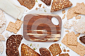 Various types of healthy bread and crispbreads with empty cutting board