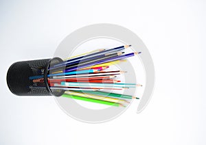 Various types of pencils and crayons placed in a jar which have fallen on a white desk