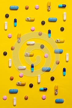 Various types of pills on yellow background photo