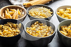 Various types of raw italian pasta in bowls
