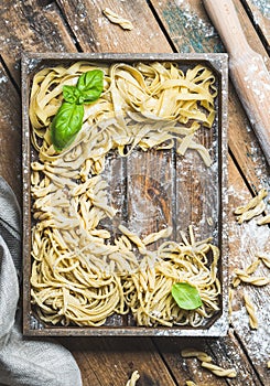 Various uncooked Italian pasta in wooden tray over rustic background