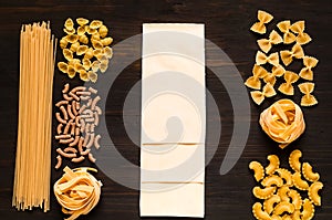 Various uncooked pasta on dark wooden background. Food concept. Flat lay. Top view
