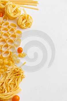 Various uncooked pasta on white wooden background. Top view. Italian pasta for restaurant with space for text