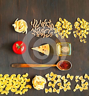 Various uncooked pasta and wooden spoon with spices on dark background