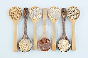 Various varieties of rice and wholegrains in spoon on wooden tab