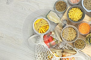 Various vegan organic products in glass jars and bowls on a white wooden background.