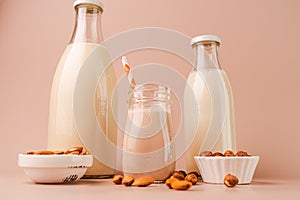 Various vegan plant based milk and ingredients. Dairy free milk substitute drinks on pink background, closeup view