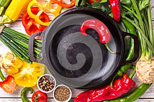 Various vegetables ingredients on wooden table around frying pan