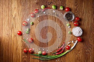 Various vegetables, seasoning and spicies around blank plate on rustic wooden background, top view