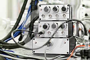 Various wires and cables connected to 3 science laboratory electric signal processing and measurement devices with knobs and