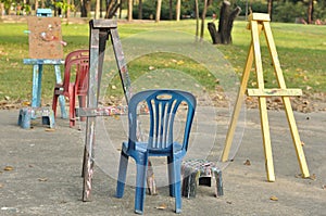 Various wooden easels with plastic chairs in public garden.