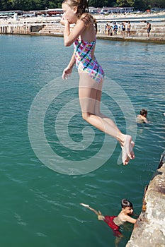 Girl jumping into the sea from the pier