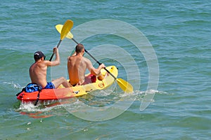 Two young men are sailing on a kayak in the sea