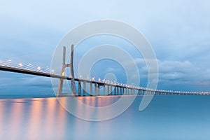 Vasco da Gama suspension bridge with lights at sunset in Lisbon, Portugal