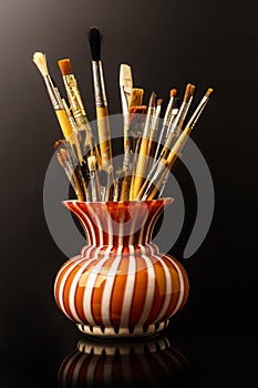 Vase with artistic brushes on the black background