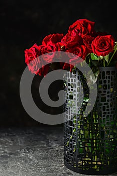 Vase with beautiful bouquet of red roses on dark background