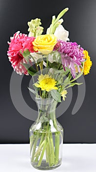 VASE WITH BEAUTIFUL COLORFUL BRIGHT FLOWERS ISOLATED IN DARK BACKGROUND.