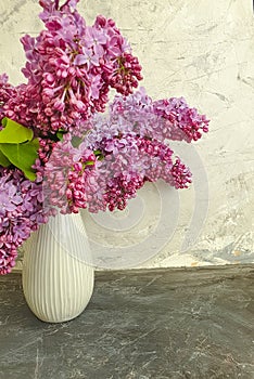 Vase bouquet of lilac on gray concrete