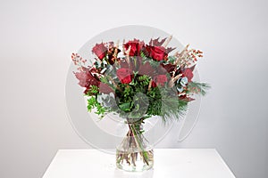 Vase with a bouquet of red and green Christmas flowers on a neutral background photo