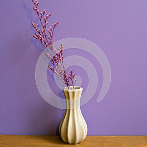 Vase of dry flowers on wooden table. purple wall background. retro style. home interior