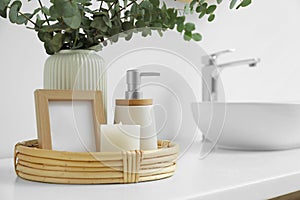 Vase with eucalyptus branches and toiletries near vessel sink in bathroom, space for text. Interior design