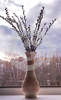 A vase with flowering willow twigs stands on the windowsill.