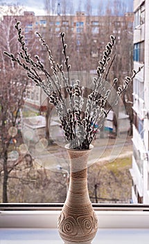 A vase with flowering willow twigs stands on the windowsill.