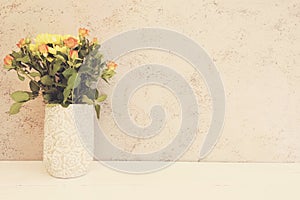 Vase of flowers. Rustic vase with orange roses and yellow chrysanthemums. White background, empty place, copy space. Vintage tinte photo