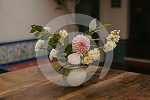 a vase with flowers sitting on a table in front of a tiled wall