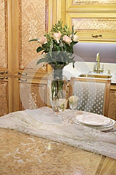 Vase with flowers on a table on a wooden kitchen background