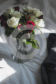 Vase of flowers on a white-sheeted bed