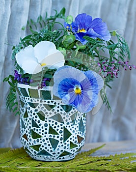 a vase made of glass with three flowers white and blue