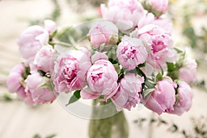 Vase of peonies in the foreground. soft focus. Workshop florist, making bouquets and flower arrangements. Woman