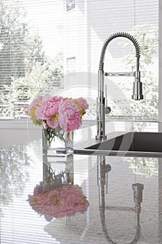 Vase of peonies on sink of modern kitchen