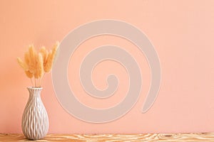 Vase of pink hares tail grass Lagurus ovatus dry flowers on wooden table